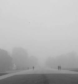 People walking on road against sky during winter