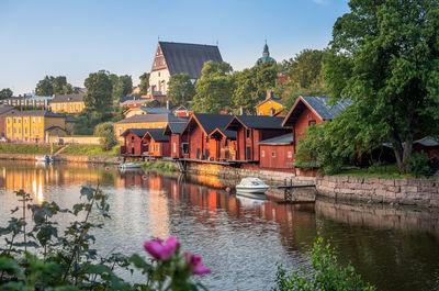 Houses by lake and buildings against sky