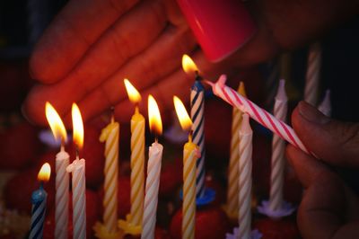 Close-up of hands igniting birthday candles