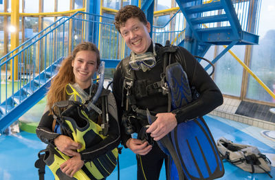 Portrait of happy friends with diving equipment standing by swimming pool