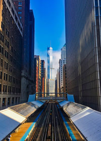 Low angle view of railroad tracks amidst buildings in city against sky