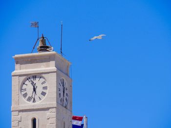 Low angle view of clock tower against clear blue sky