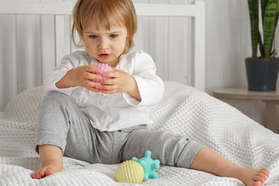 Portrait of cute girl playing with teddy bear at home