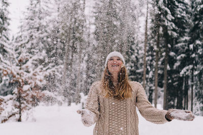 Woman standing by tree in forest during winter