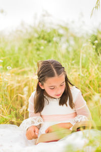 Girl reading book sitting in field