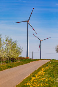 The huge towers of two wind turbines to generate electricity behind bushes and trees in germany