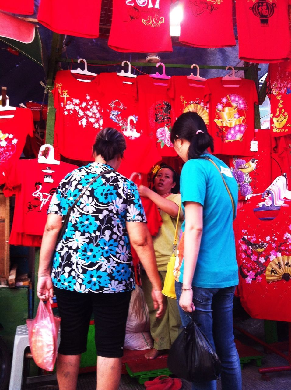 REAR VIEW OF PEOPLE IN RED SHOPPING