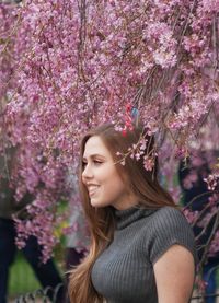 Portrait of beautiful woman with pink flower against trees