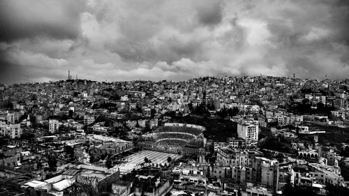 Aerial view of cityscape against cloudy sky