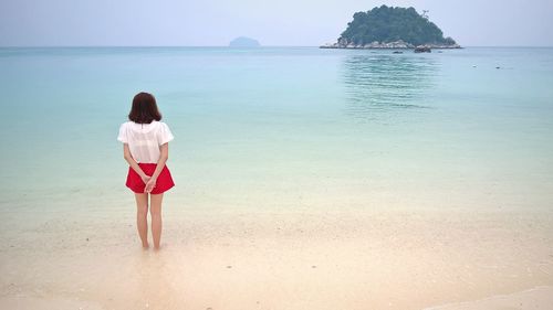 Rear view of young woman standing on beach