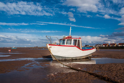 Boat moored on beach against sky