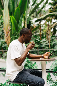 Afro american young stylish man standing in station with mobile phone at coffee shop