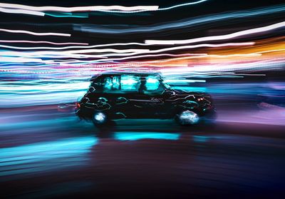 Blurred motion of car on illuminated street at night