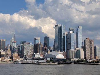 Sea by modern buildings against sky in city