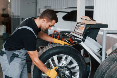 Taking the wheel. man in uniform is working in the auto service.