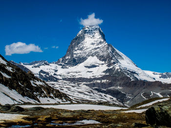 Scenic view of snowcapped mountains against blue sky