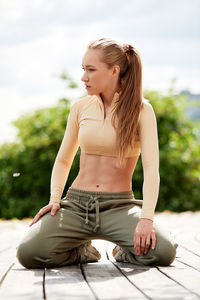 Portrait of young woman standing against trees