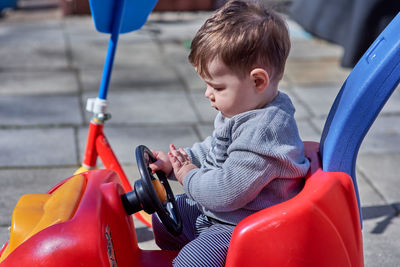 Handsome young boy toddler is playing in a red push car
