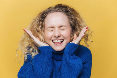 Portrait of young woman against yellow background