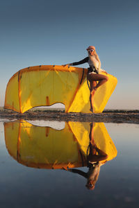 Attractive stylish young caucasian woman in cap sunglasses and kitesurfer outfit standing next to