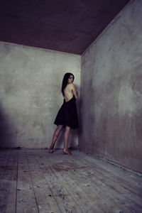 Full length of woman standing against wall