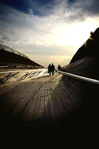 People walking on boardwalk at sunset
