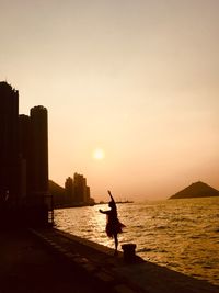 Silhouette man on beach by sea against sky during sunset