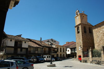 Street amidst buildings in city against clear blue sky