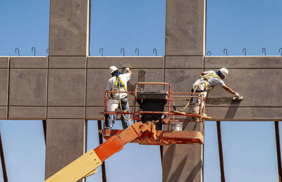 Low angle view of men working at construction site against sky