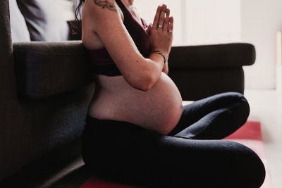 Midsection of pregnant woman exercising while sitting at home