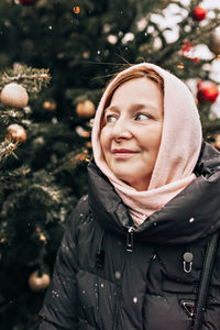 A young woman warmly dressed on the street against the background of christmas on a snowy cold day.