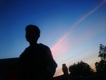 Low angle view of silhouette woman sitting against clear sky