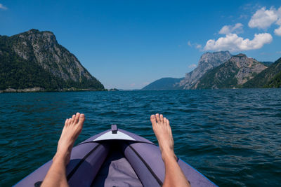 Low section of person on sea against mountains