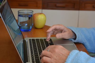 Midsection of man using laptop on table