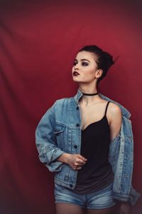 Portrait of beautiful young woman standing against red background