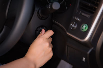 Cropped hand of woman adjusting air conditioner button in car