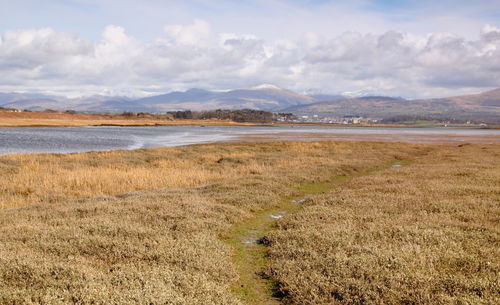 Scenic view of lake and mountains against cloudy sky