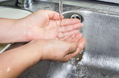 Cropped image of woman washing hands in sink