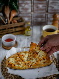 Cropped image of hand holding a slice of pizza