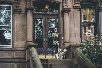 Halloween decoration of skeleton holding dogs on leash in front of the building's entry door