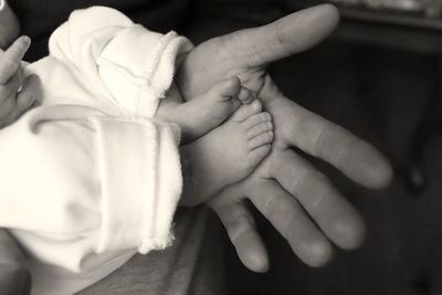 Cropped image of person hand holding baby feet