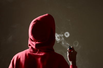 Rear view of man smoking at home