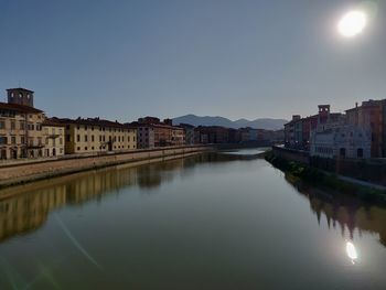 River by buildings against clear sky in city