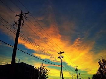 Low angle view of electricity pylon against cloudy sky