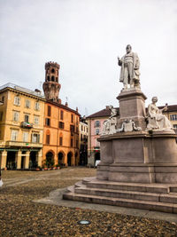 Statue in city against sky