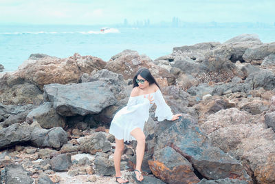 Full length of young woman standing on rock at beach