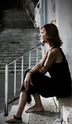 Side view of young woman sitting on railing