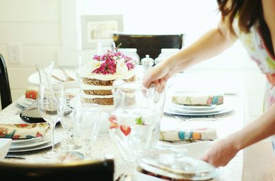 Cropped image of woman holding jug on table