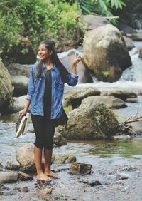 Young woman standing on rock at river