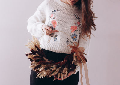 Midsection of woman holding decorated basket against white background